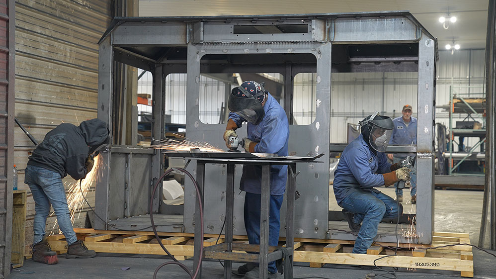 3 workers working on large operator cab