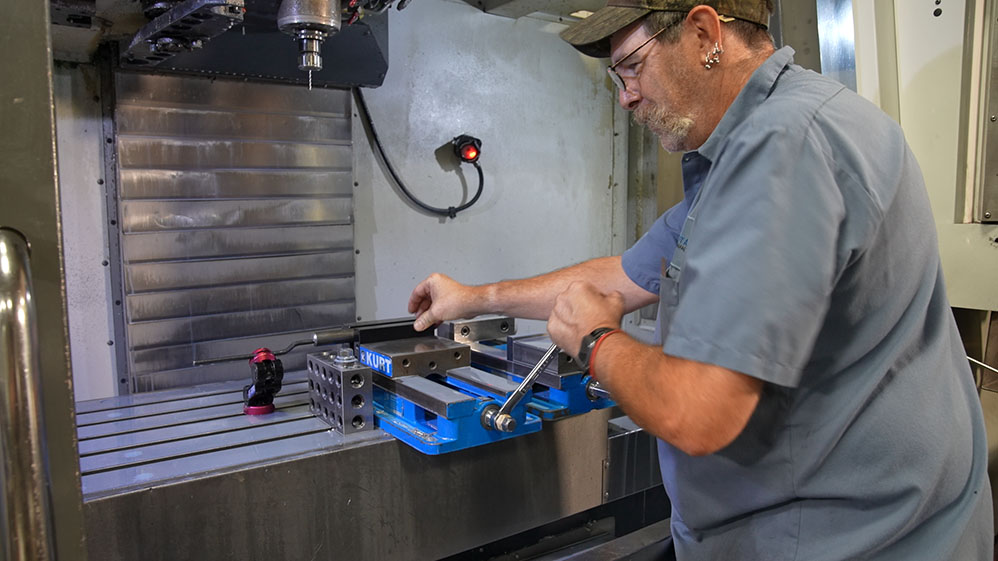 Worker sets up metal part in milling machine