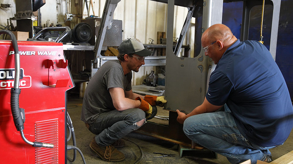 Two people examine an operator cab