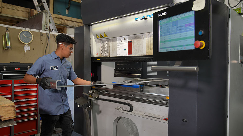 worker bending sheet metal in press brake