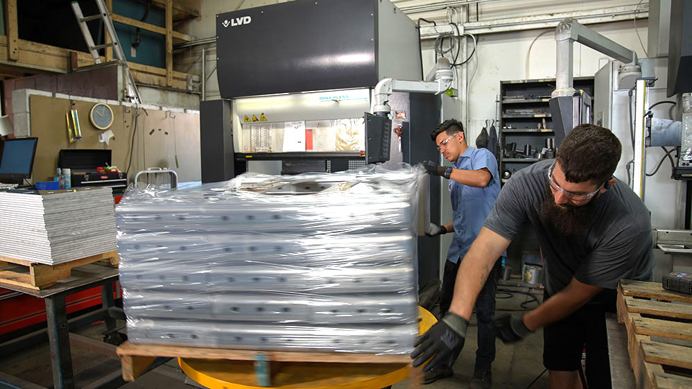 manufacturing employee wrapping parts in plastic